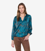 Load image into Gallery viewer, Person wearing a teal &amp; coper splash blouse and brown pants on a white background.
