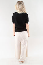 Load image into Gallery viewer, Woman wearing a black top and white pants on a white background
