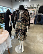 Load image into Gallery viewer, Mannequin wearing a patterned dress and black hat in a store setting
