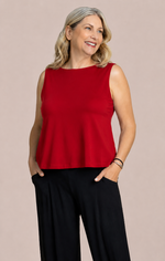 Load image into Gallery viewer, A woman modeling a sleeveless red peplum-style top with black wide-leg pants, standing against a solid light beige studio background.
