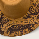 Load image into Gallery viewer, Close-up of suede hat with 'Who Loves Country Music' text and floral design on a white background
