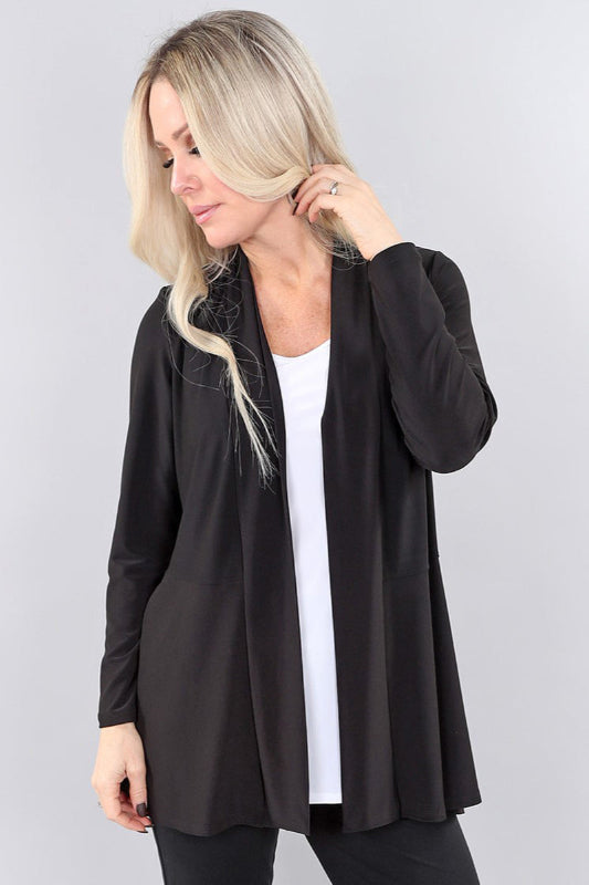Woman wearing a black cardigan over a white top on a plain background