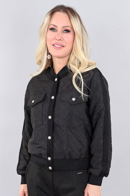 Woman wearing a black quilted jacket against a gray background