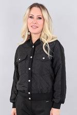 Load image into Gallery viewer, Woman wearing a black quilted jacket against a gray background
