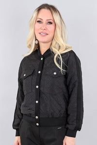 Woman wearing a black quilted jacket against a gray background