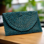 Load image into Gallery viewer, Teal woven clutch bag on a wooden surface with a blurred background
