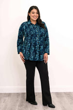 Load image into Gallery viewer, Woman wearing a blue floral patterned shirt and black pants against a white background
