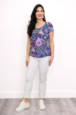 Load image into Gallery viewer, Woman wearing a colorful patterned top and white pants on a plain background

