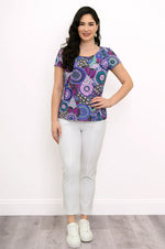 Load image into Gallery viewer, Woman wearing a colorful patterned top and white pants on a plain background
