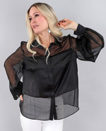Load image into Gallery viewer, Woman wearing a black sheer chiffon blouse with white pants on a gray background
