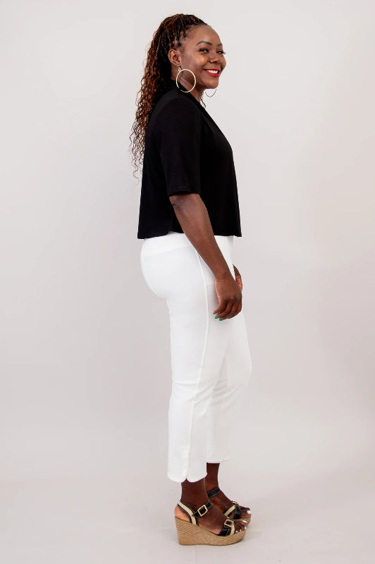 Woman wearing a black top and white pants on a plain background