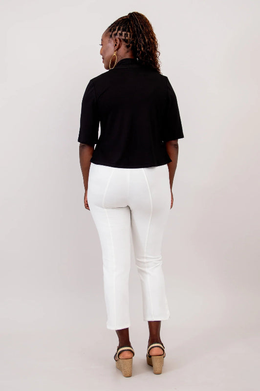 Person wearing a black top and white pants on a plain background