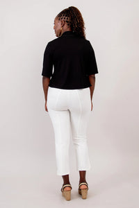 Person wearing a black top and white pants on a plain background