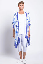 Load image into Gallery viewer, Woman wearing a blue and white patterned kimono-style garment over a white outfit on a white background
