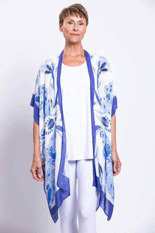 Woman wearing a blue floral kimono over a white outfit on a light gray background