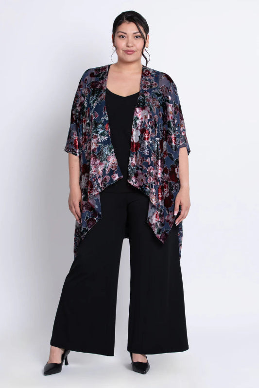 Woman wearing a floral velvet kimono over a black outfit on a white background