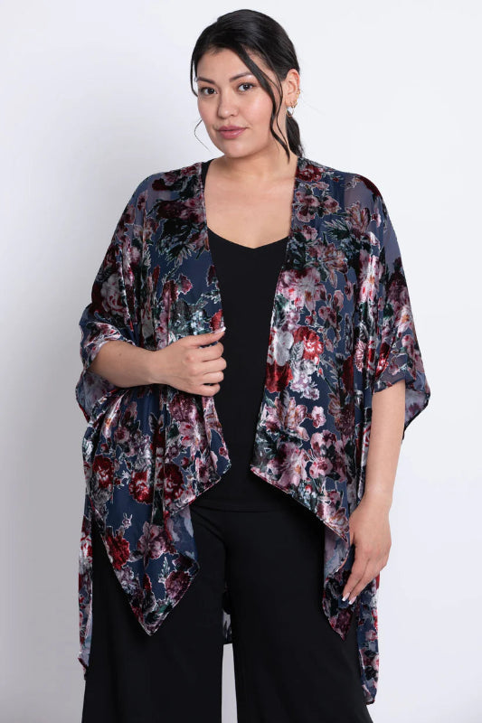 Woman wearing a floral velvet kimono over a black outfit on a white background