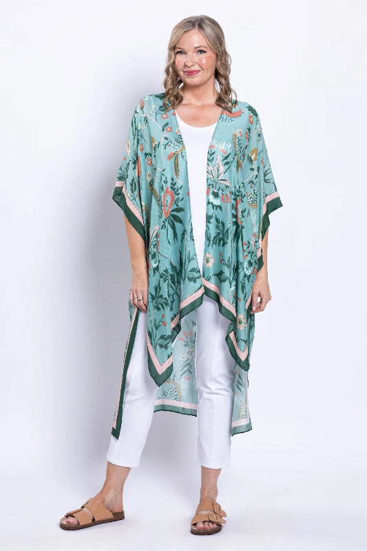 Woman wearing a green floral kimono over a white outfit on a white background
