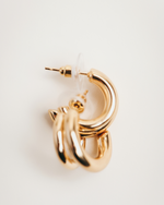 Load image into Gallery viewer, Gold hoop earring on a light beige background
