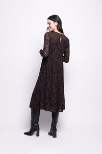 Woman wearing a brown mesh with black velvet dress and black boots on a white background