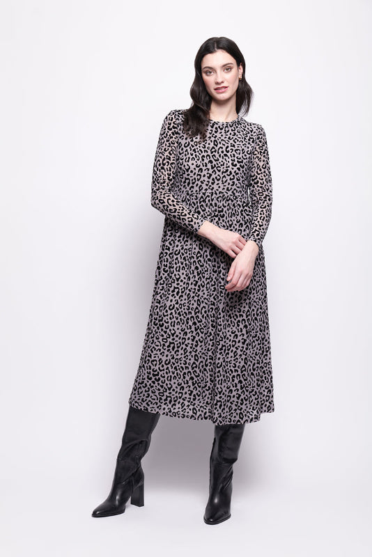 Woman wearing a grey mesh with velvet leopard print dress with black boots on a white background
