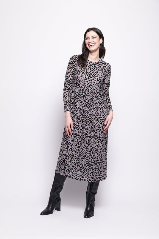 Woman wearing a grey mesh with velvet leopard print dress with black boots on a white background