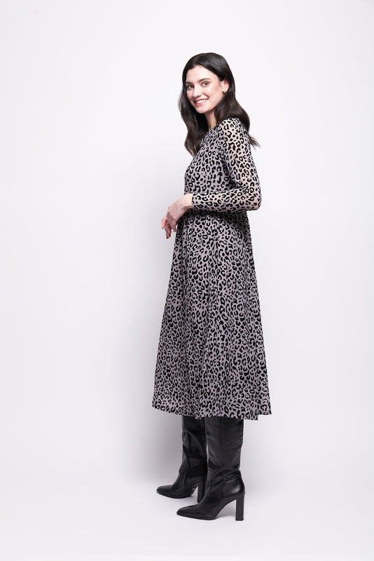 Woman wearing a grey mesh with velvet leopard print dress with black boots on a white background