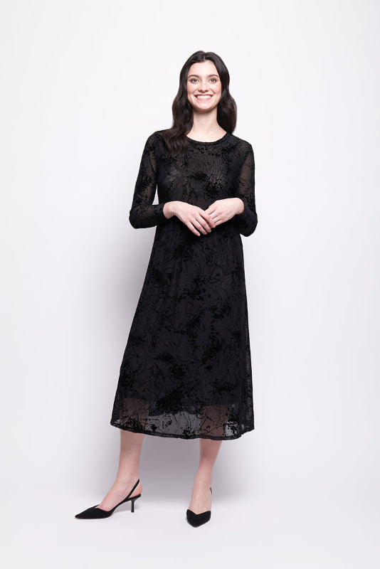 Woman wearing a black mesh with black velvet print dress on a white background