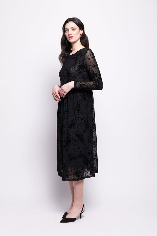 Woman wearing a black mesh with black velvet print dress on a white background