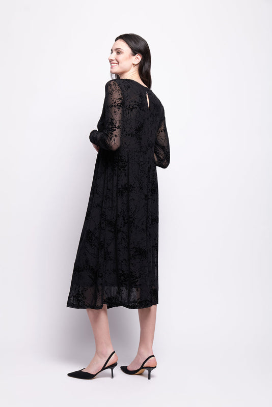 Woman wearing a black mesh with black velvet print dress on a white background