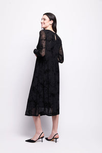 Woman wearing a black mesh with black velvet print dress on a white background
