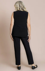 Load image into Gallery viewer, A woman shown from the back wearing a sleeveless black vest and matching black pants against a solid beige studio background.
