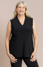 Load image into Gallery viewer, A woman with blonde hair wearing a sleeveless black V-neck top and black pants, standing against a solid beige studio background.
