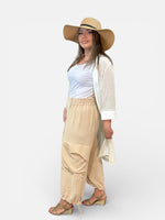 Load image into Gallery viewer, Woman wearing a white top, beige pants, and a wide-brimmed hat on a white background
