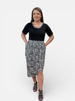 Load image into Gallery viewer, Woman wearing a black top and zebra print skirt on a white background

