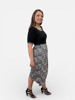 Load image into Gallery viewer, Woman wearing a black top and zebra print skirt on a white background
