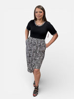 Load image into Gallery viewer, Woman wearing a black top and zebra print skirt on a white background
