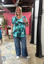 Load image into Gallery viewer, Woman taking a mirror selfie wearing a green marble-patterned shirt and blue jeans in a store.
