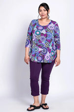 Load image into Gallery viewer, Woman wearing a colorful patterned top and purple pants on a white background
