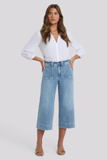 Load image into Gallery viewer, Woman wearing a white blouse and light blue jeans on a plain background

