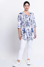 Load image into Gallery viewer, Woman wearing a blue floral blouse and white pants on a white background

