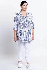Load image into Gallery viewer, Woman wearing a blue floral blouse and white pants on a white background
