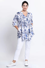 Load image into Gallery viewer, Woman wearing a blue floral blouse and white pants on a white background
