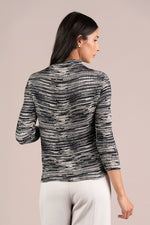 Load image into Gallery viewer, A woman shown from the back wearing a black and white textured Plisse Mock top with three-quarter sleeves and white pants, set against a solid light beige background.
