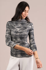 Load image into Gallery viewer, A woman wearing a black and white textured Plisse mock neck top with three-quarter sleeves, paired with white pants.
