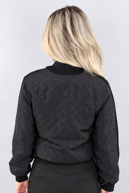 Person wearing a black quilted jacket against a plain background