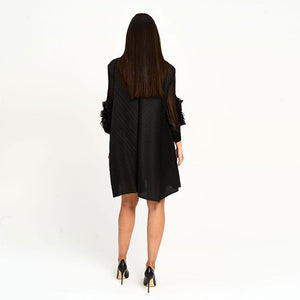 Woman wearing a black dress with sheer sleeves on a white background