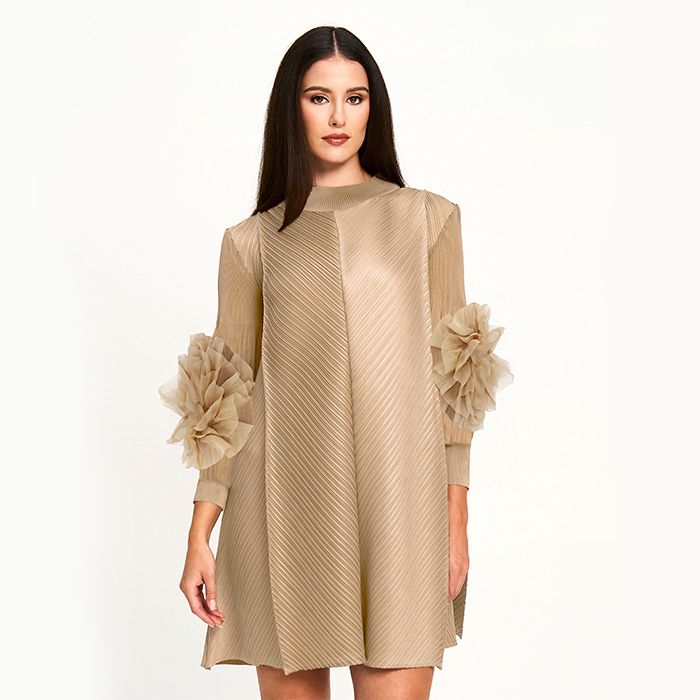 Woman wearing a beige dress with floral details on a white background