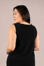 Load image into Gallery viewer, A woman shown from the back wearing a sleeveless black top against a plain beige studio background.
