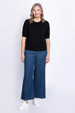 Load image into Gallery viewer, Woman wearing a black top and blue pants on a white background
